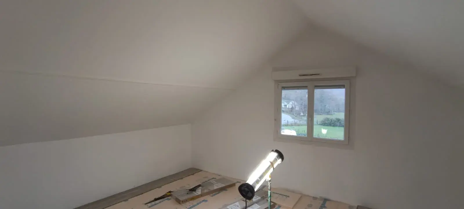Combles terminés : murs et rampants blancs autour de la fenêtre