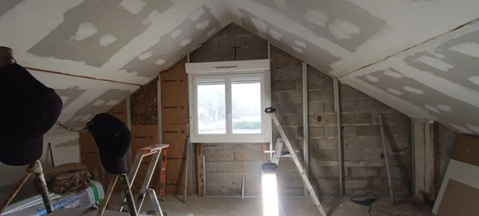 Combles en cours de travaux : plaques de plâtre jointées, isolant et parpaings apparents