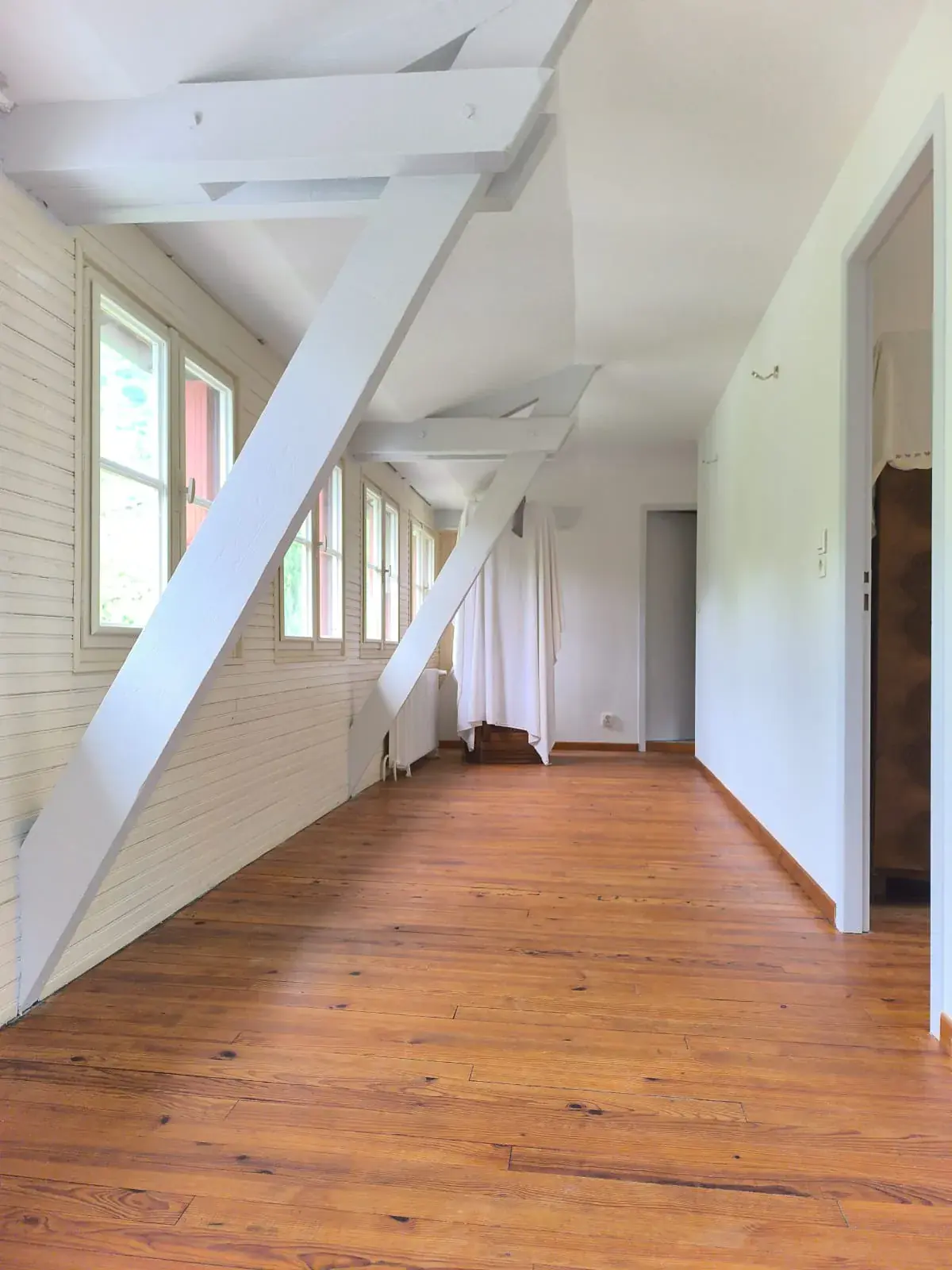 Étage rénové : poutres peintes en blanc, murs clairs et parquet en bois