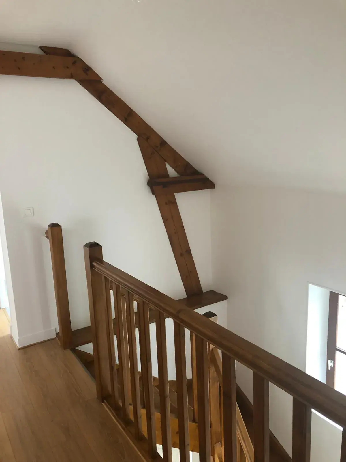 Mezzanine aux murs blancs, charpente apparente en bois et garde-corps