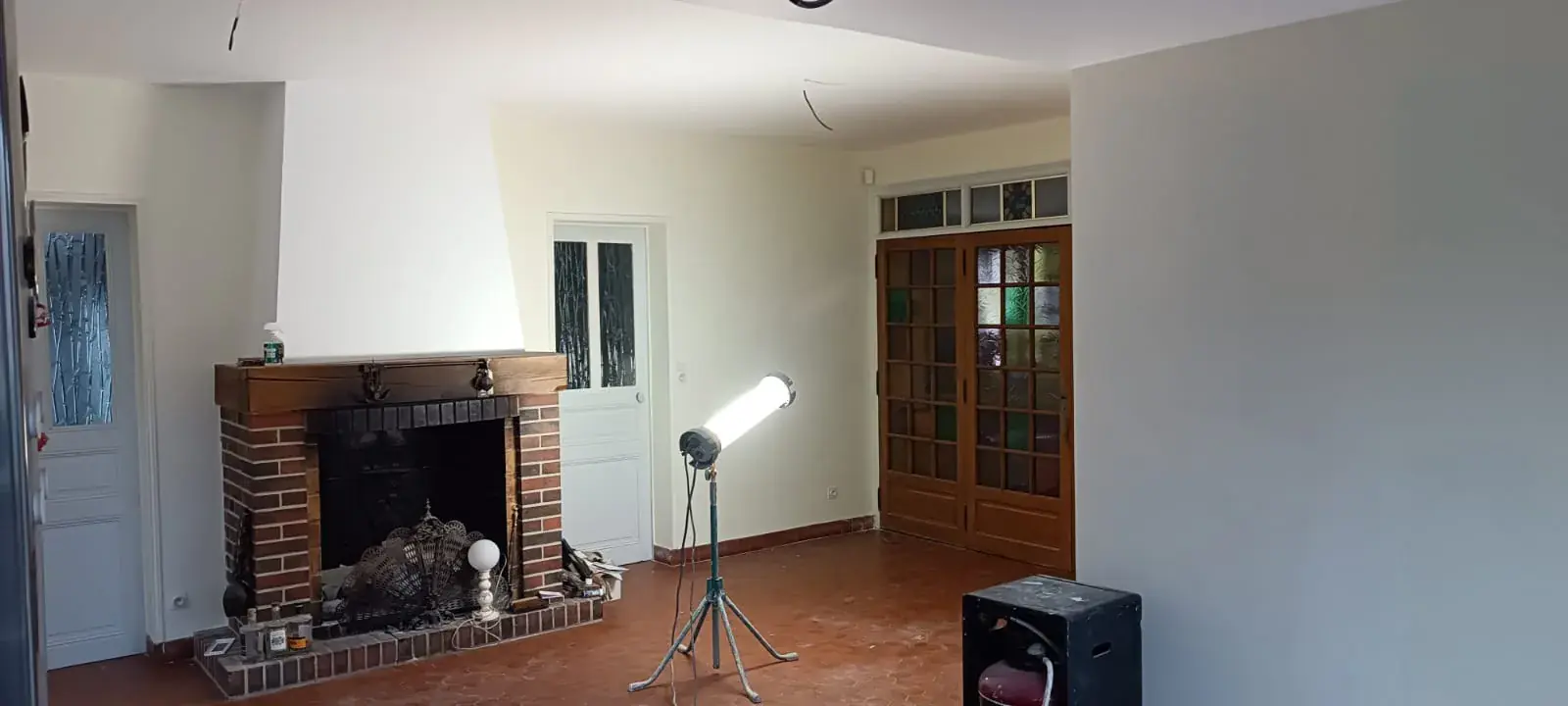 Séjour en cours de rénovation, murs et plafond repeints autour d'une cheminée en brique
